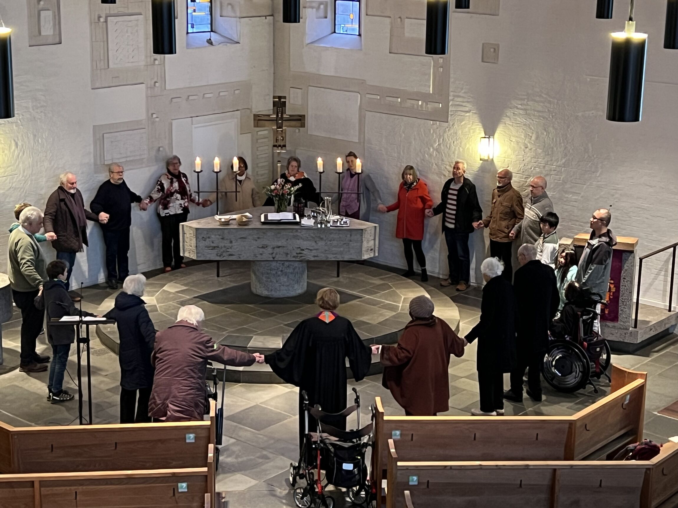 Menschen aus der Christophorusgemeinde stehen im Kreis um den Altar und reichen sich nach dem Abendmahl die Hände
