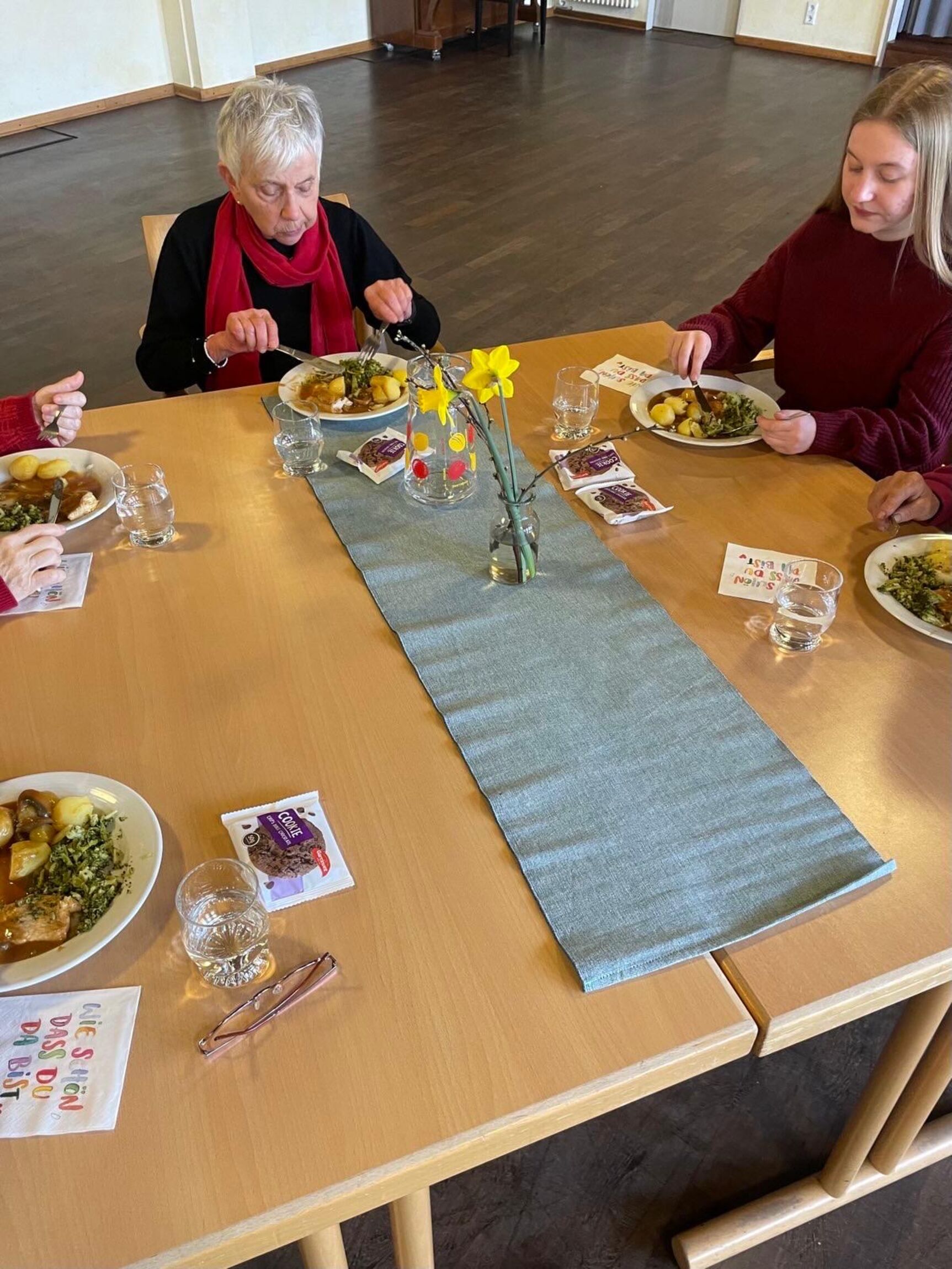 Ein gedeckter Tisch, mehrere Menschen essen gemeinsam, zwei Frauen sind erkennbar