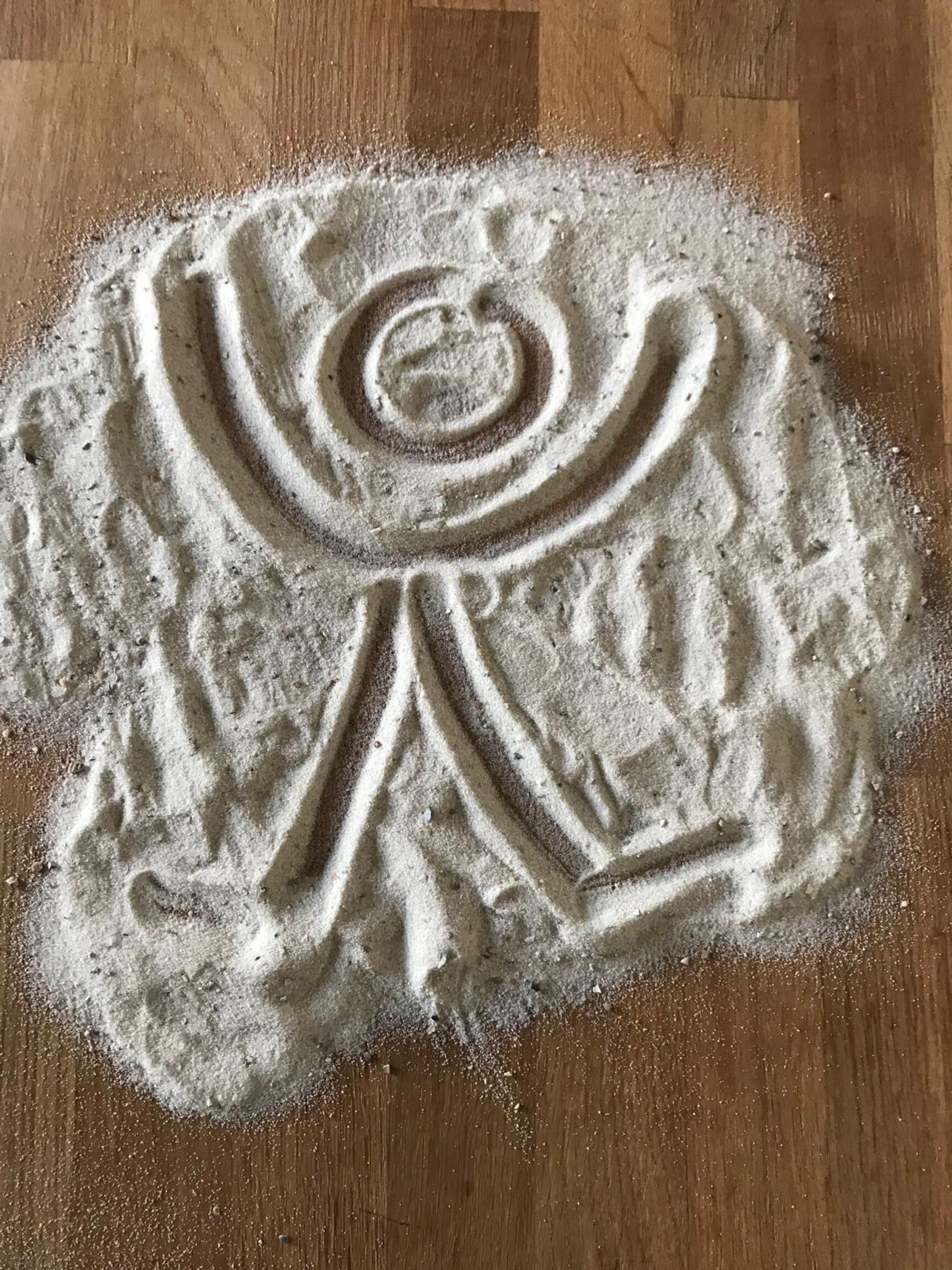 Im Sand mit Finger gemalter Engel