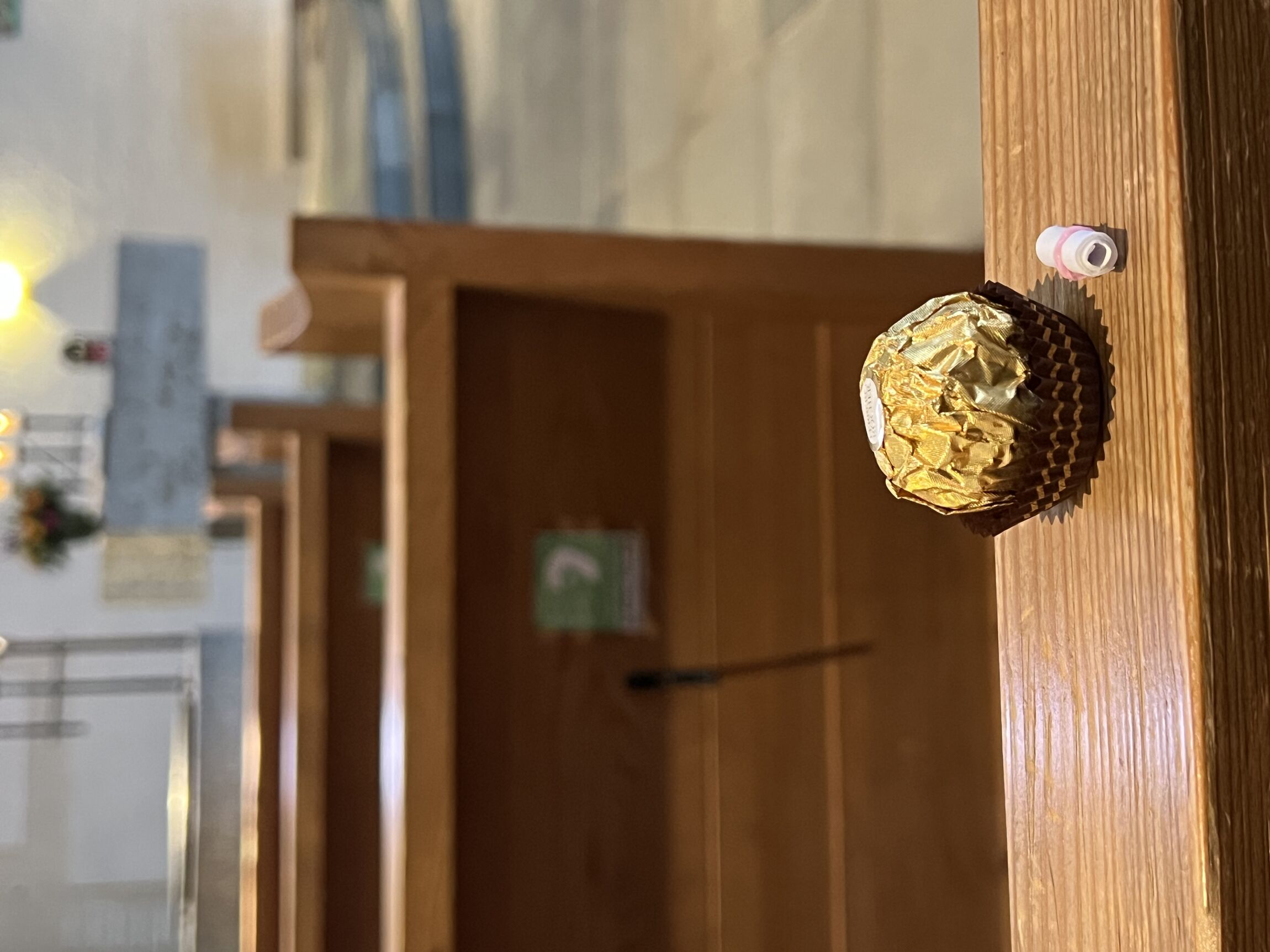 Schokokugel und Mini-Papierrolle auf einer Kante einer Kirchenbank in der Christophoruskirche