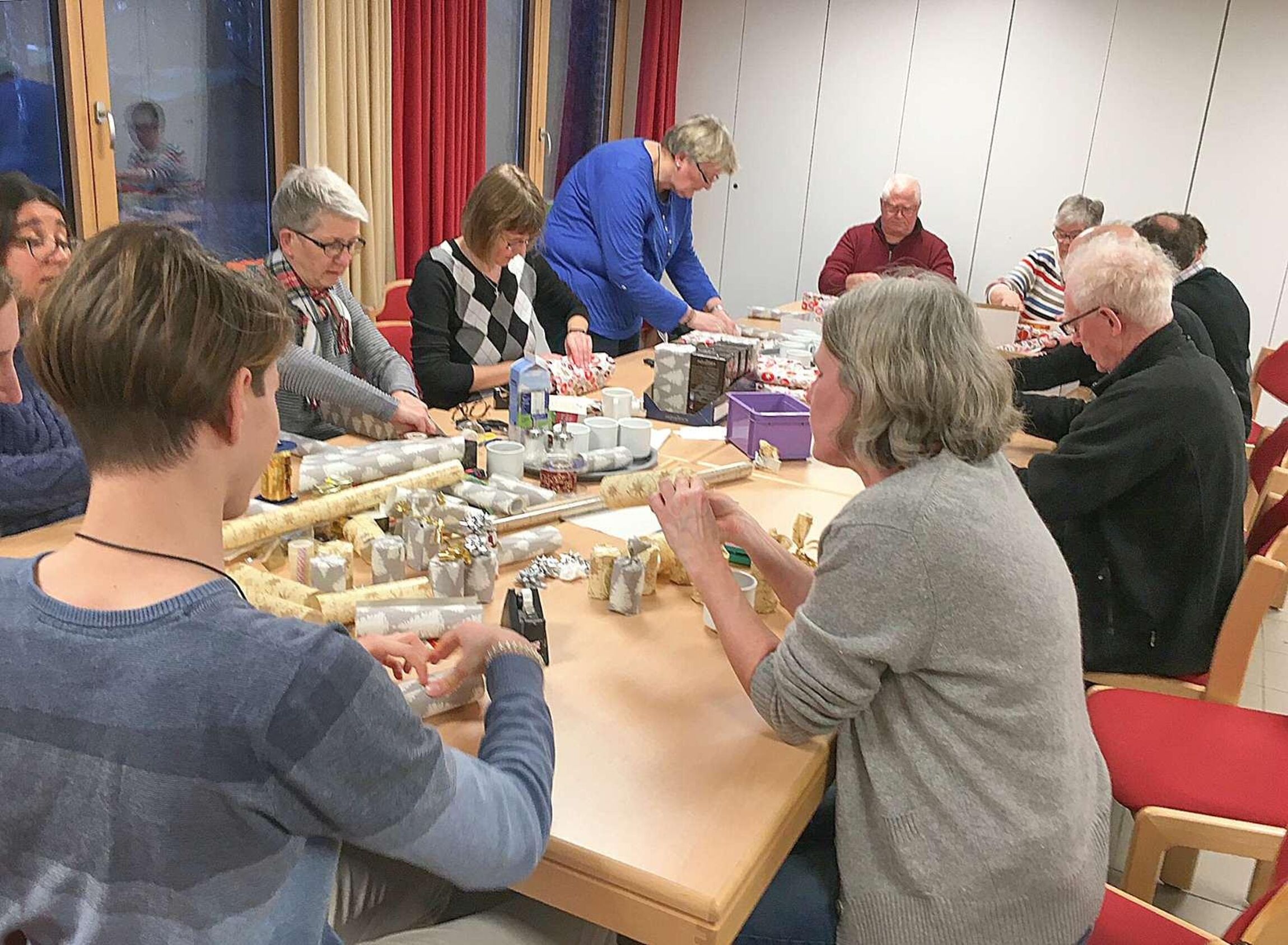 Menschen sitzen am Tisch und verpacken Geschenke