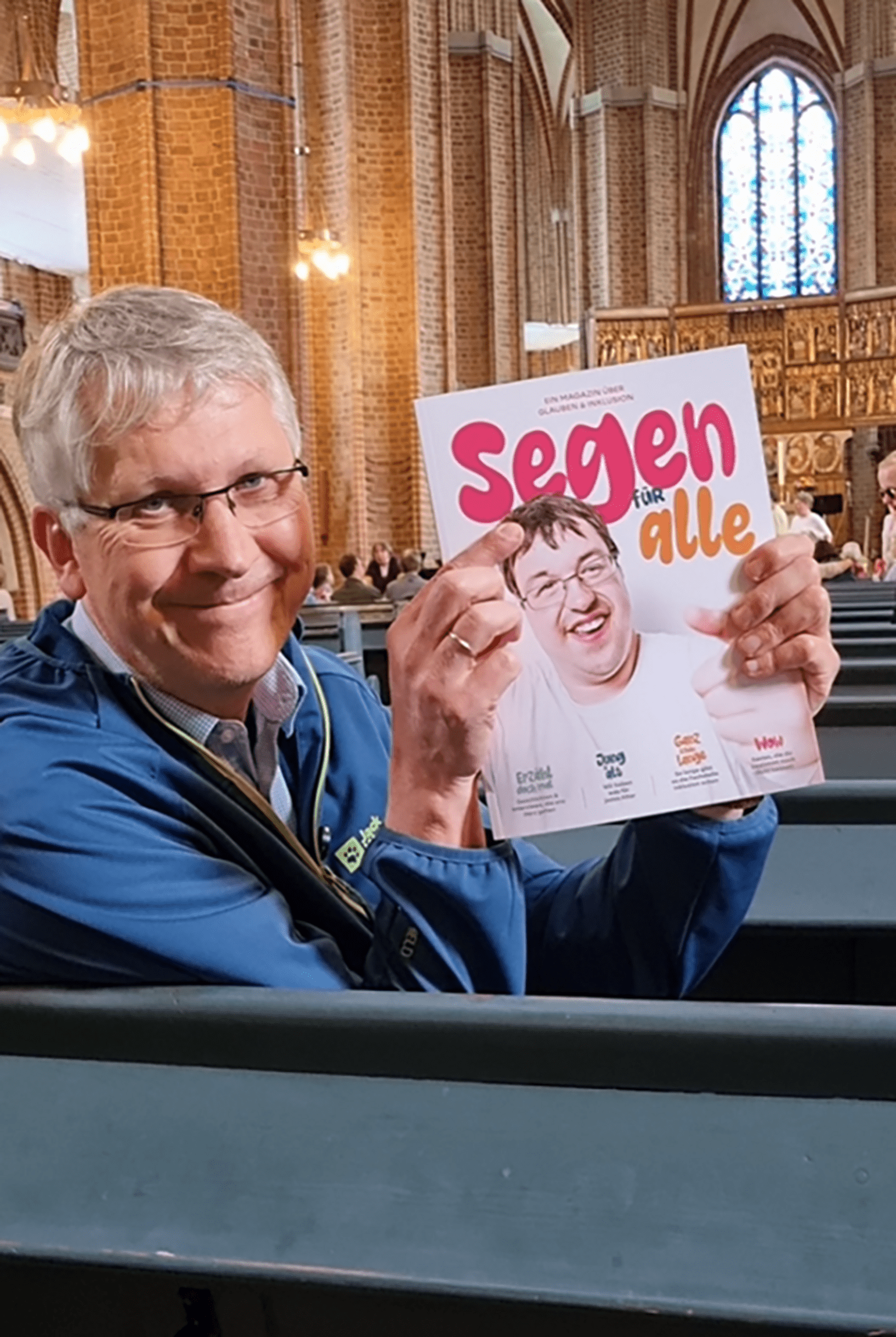 Mann zeigt Magazin mit dem Titel "Segen für alle"