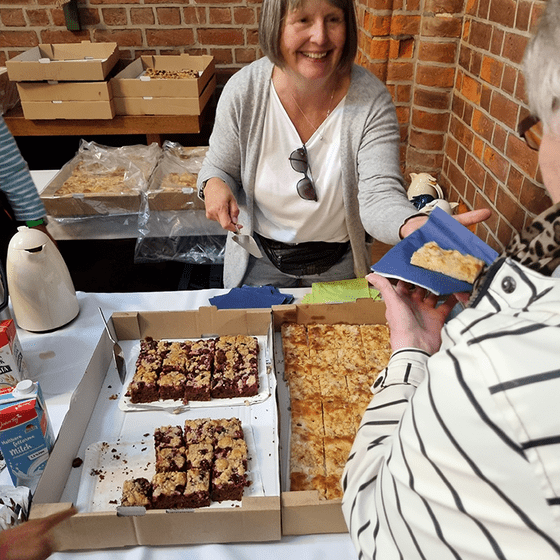 Freundlich lächende Frau gibt Kuchen aus