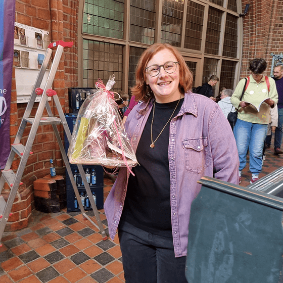 Frau mit einem Geschenk in der Hand lächelt in die Kamera