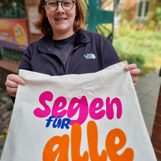 Frau zeigt die bedruckte Vorderseite eines Stoffbeutels