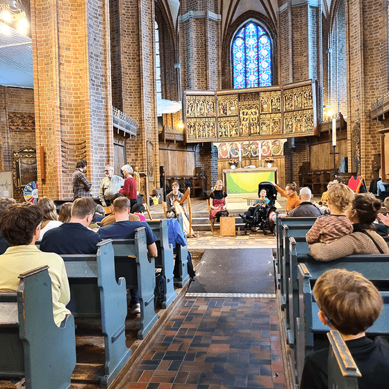 Kirchraum mit Menschen, die zur Band Richtung Altar schauen