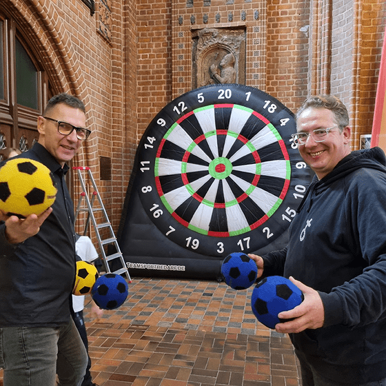 zwei Männer halten Bälle für das Fußalldart in der Hand