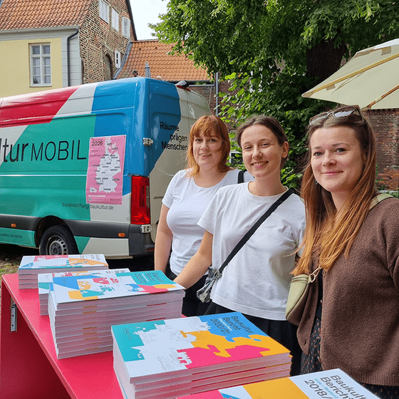 drei Frauen aus dem Team der Bundesstiftung Baukultur stehen am Infostand mit Broschüren