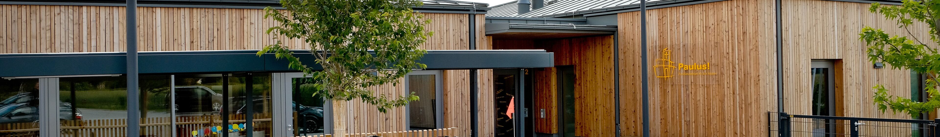 Außenansicht Familienzentrum an den Hecken. Zu sehen sind Fahrradständer und der Eingang ins Familienzentrum